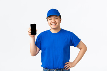 Technology, online shopping and shipping concept. Portrait of friendly-looking smiling asian delivery man in blue uniform announce application for tracking orders, showing smartphone screen