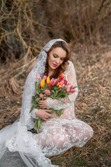 Canvas Print - Shallow focus shot of a pregnant Caucasian woman wearing a white wedding dress and holding flowers