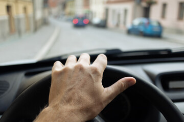 Poster - Car interior - hand on steering wheel with blurred cars on street on background