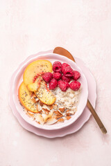 Wall Mural - Porridge oatmeal with raspberries, peaches and nuts for breakfast. Healthy vegetarian food concept.