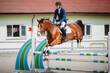 closeup portrait of gelding horse and handsome man rider jumping obstacle