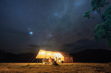 couple tourist resting in yellow tent camping on hill with starry in the night sky