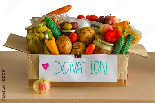 Box with food donations on light table is isolated on white background. Grocery set to help those in need. Donation box different products. Concept food donations box with cereals, vegetables, fruits.