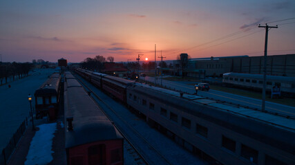 Wall Mural - Sunrise With Blue, Red Sky and Clouds Looking Over a Train Station and Yard