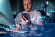 © VideoFlow - Businessman in casual wear using smart phone to optimize trading strategy at corporate finance fund. Forex chart hologram over modern office background at night time