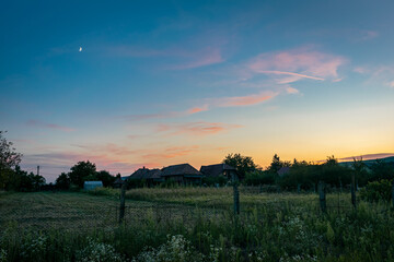 Wall Mural - purple clouds with moon over the romanian landscape at dusk