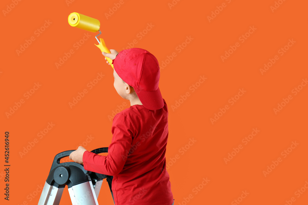 Little boy painting wall in room