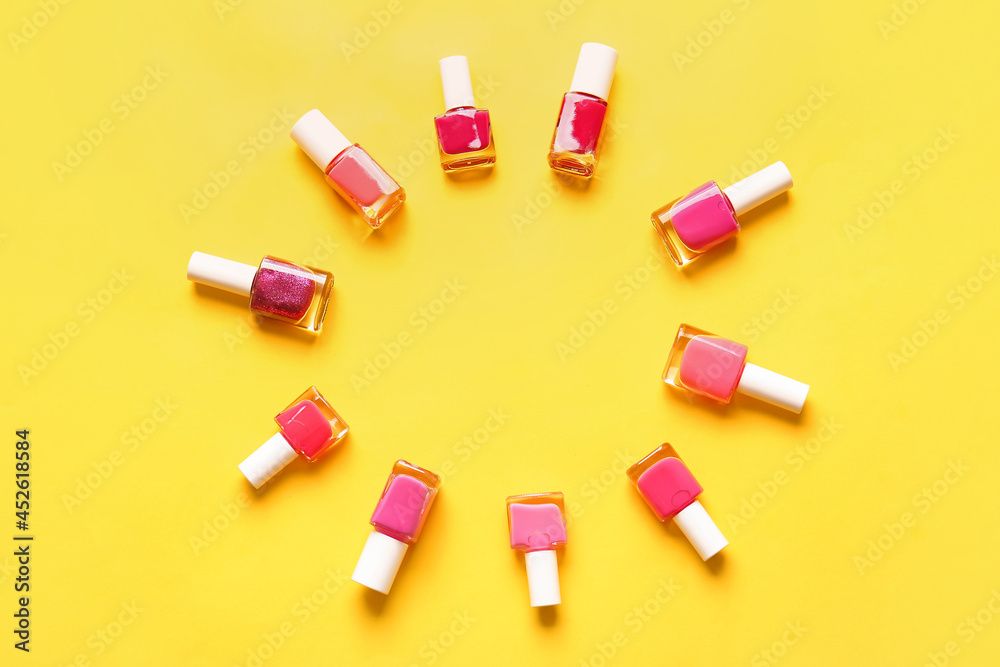 Frame made of nail polish bottles on color background
