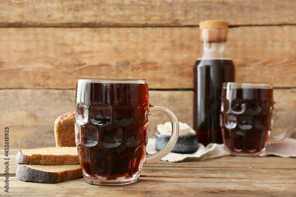 Mug of fresh kvass on wooden background