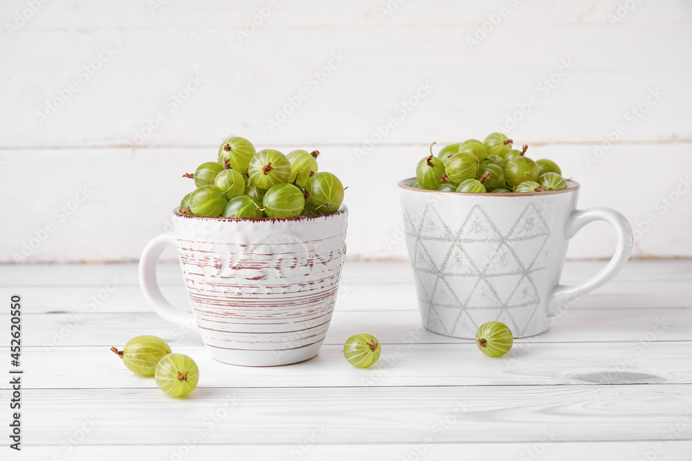 Cups with fresh ripe gooseberry on table