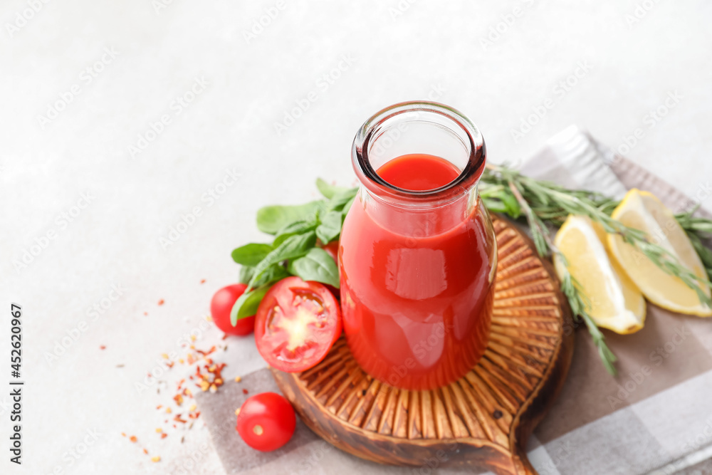 Bottle of tasty tomato juice on light background