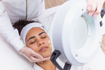 Wall Mural - woman in beauty clinic doing a facial evaluation. Woman doing aesthetic treatment