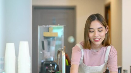 Wall Mural - Young beautiful Asian woman coffee shop employee barista working at cafe. Smiling female cashier taking order and serving to customer on counter. Small business owner and part time job working concept