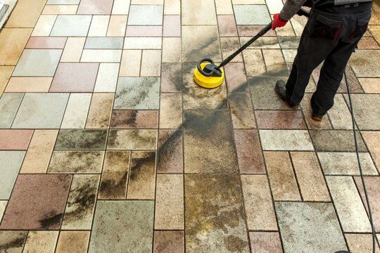 cleaning stone slabs on patio with the high-pressure cleaner. person worker cleaning the outdoors fl