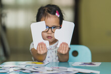 Cute Little Asian Girl Wearing Eyeglasses Playing Jigsaw Puzzle At Home