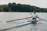 Sportsman single scull man rower rowing on boat at lake river