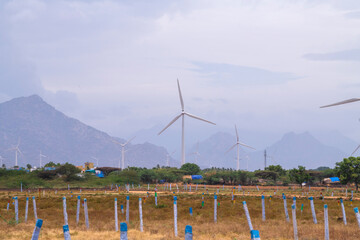 Windmill - Wind turbine below the mountain on the agriculture land. Alternate energy source generator with environment friendly. Wind turbines for ecological power supply .