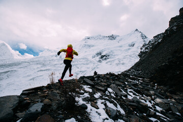 Woman trail runner cross country running up to winter snow mountain top