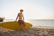 © Drobot Dean - Surfer sitting on surfboard on sandy beach coast