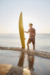 © Drobot Dean - Young surfer stand with surfboard on beach coast