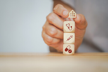 Canvas Print - senior human hand holding mini wood house and medical icon on wooden cubes for annual health checking, health and medical, family health insurance, wellness, wellbeing concept