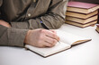 © Helios4Eos - Male hand writing in a notebook with a pen on the office desk.