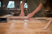 Close Up Of Furniture Maker Feeding A Board Through A Tablesaw In The Woodshop