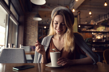 Canvas Print - Young woman with cup of coffee at cafe in morning