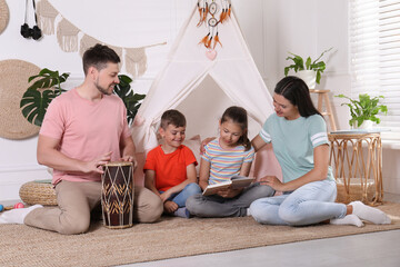 Happy family spending time together near toy wigwam at home