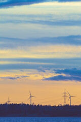 Poster - Mesmerizing  view of Electrical wind farm against blue orange sky, sea and hills on the horizon