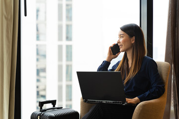 Asian businesswoman using laptop working in hotel room remotely on her business travel