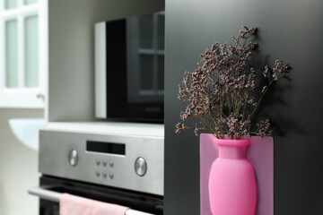 Canvas Print - Silicone vase with beautiful violet flowers on fridge in kitchen, space for text