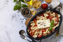 Baked feta pasta, or Tiktok pasta on gray background. Oven baked feta pasta made of tomatoes, feta cheese, garlic and herbs. Top view flat lay background. Copy space.