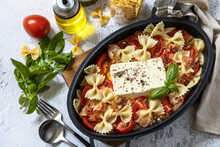 Baked feta pasta, or Tiktok pasta on gray background. Oven baked feta pasta made of tomatoes, feta cheese, garlic and herbs. Top view flat lay background.