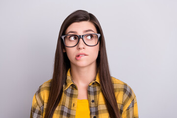 Poster - Photo of young girl bite lips worried nervous think look empty space isolated over grey color background