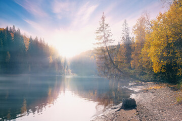Wall Mural - a wonderful autumn landscape. a fabulous lake with morning fog under the sunlight. a dramatic impres