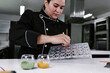 latin woman pastry chef wearing black uniform in process of preparing delicious sweets chocolates at kitchen in Mexico Latin America, mexican chocolate