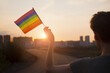 Transgender woman holding rainbow flag on sky background, LGBTQ pride, parade, march concept