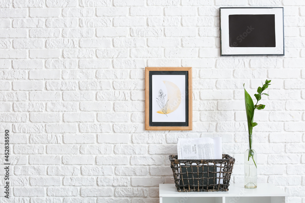 Basket with books and vase on shelf near brick wall