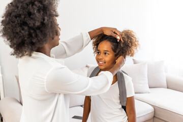 Wall Mural - Mother preparing her daughter for first day in school. Mother and daughter. Mom accompanies her child to school. Beautiful young African American mother preparing her little daughter for school