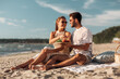 © Syda Productions - leisure, relationships and people concept - happy couple with food eating and having picnic on beach