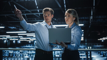 Poster - Data Center Female e-Business Enrepreneur and Male IT Specialist talk, Use Laptop. Two Information Technology Professionals on Bridge Overlooking Big Cloud Computing Server Farm.