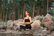 © Anna - Woman in black sport suit is doing meditation, yoga pose (asana), work out outside near beautiful river and beautiful landscape with wild nature