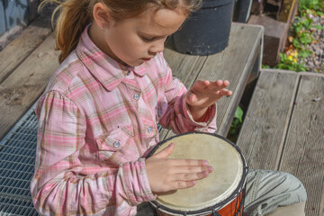 the girl child with a djembe drum outdoor on the porch of the house photo without processing