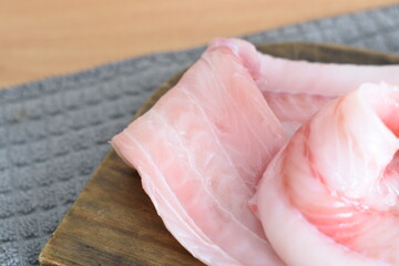 some hake fillets on a wooden board on the table