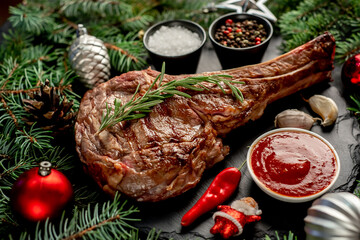 Grilled Christmas tomahawk steak with fir tree and tree decorations on stone background