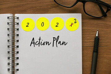 Fototapete - Green label sticker written with Year 2022 on a notebook written with Action Plan.