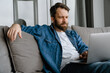 © Drobot Dean - Bearded european man working with laptop while sitting on sofa at home