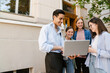 © Drobot Dean - Multiracial students using laptop and laughing while standing outdoors