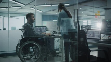 Disability-Friendly Office: Happy IT Programmer with Disability in a Wheelchair Talks with Colleague while Working on Computer. Software Engineers Develop Innovative App, Program. Medium Shot